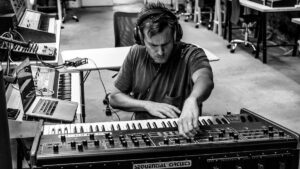 Clark in studio circondato da sintetizzatori e tastiere analogiche