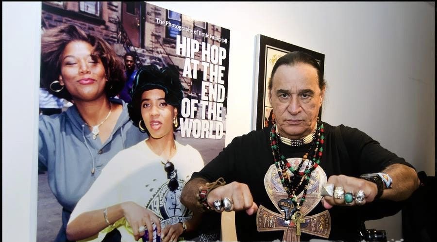 Ernie Paniccioli davanti al poster Hip Hop at the End of the World con immagine di Queen Latifah