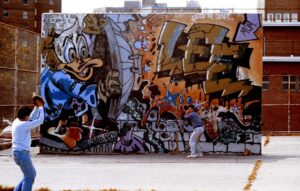 Ernie Paniccioli davanti a un murale di Lee, graffiti writer pioniere di New York