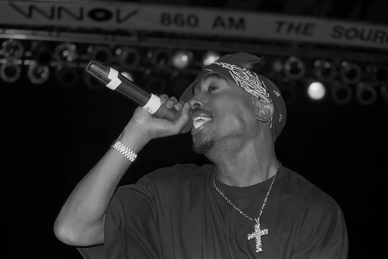 Tupac Shakur in concerto, anni '90, microfono in mano, espressione intensa