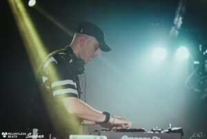 Alix Perez durante un DJ set dal vivo, cuffie al collo e mixer in primo piano