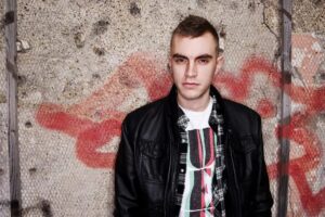 Ritratto giovanile di Alix Perez davanti a un muro con graffiti colorati