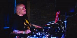 Ice One alla consolle durante un DJ set in un club con luci blu