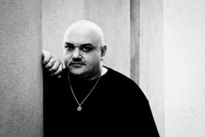 Ritratto in bianco e nero di un giovane Ice One appoggiato a una parete di Roma