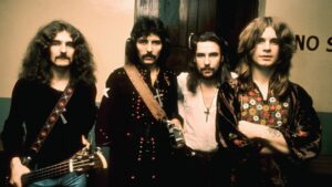 I Black Sabbath in posa in un corridoio negli anni Settanta, con basso e croci al collo