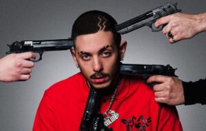 Enzo Dong ritratto in studio circondato da pistole in un'immagine artistica dai toni gangsta