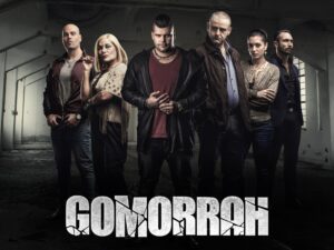 Il cast della serie tv Gomorra in posa in un capannone abbandonato, con il logo dello show in basso
