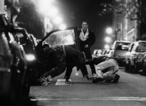 Scena notturna in bianco e nero da La Haine, con i protagonisti in strada tra le auto parcheggiate