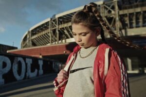 Fotogramma da un videoclip di Liberato con una ragazza davanti a uno stadio e la scritta Napoli