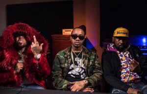 I tre rapper di Griselda Records seduti in studio, con giacche vistose, davanti a una consolle