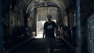 Militant A cammina nel tunnel del Forte Prenestino a Roma con la maglietta degli Assalti Frontali