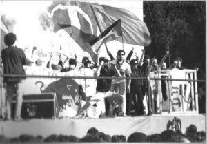 Gli Onda Rossa Posse sul palco il 3 febbraio 1990, foto in bianco e nero con bandiere e pubblico