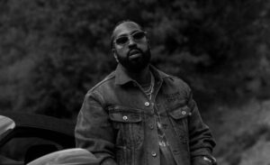 Roc Marciano in bianco e nero con occhiali da sole e giacca di jeans all'aperto