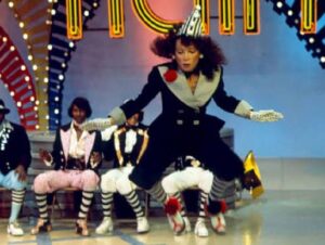 Toni Basil in costume durante un'esibizione televisiva con i ballerini del Locking sullo sfondo