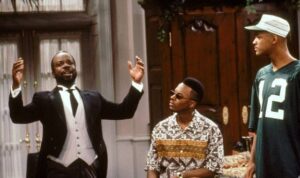 Geoffrey a braccia aperte, Jazz con occhiali scuri e Will Smith in maglia numero 12 in una scena di Willy, il principe di Bel-Air