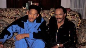 Will Smith in tuta blu e Quincy Jones seduti sul divano, produttori e protagonisti di Willy, il principe di Bel-Air